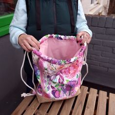 a woman holding a pink bag on top of a wooden table next to a brick wall