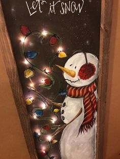 a snowman is standing in front of a christmas tree with lights and let it snow written on the door