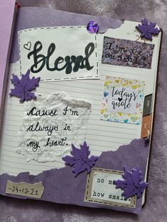 an open journal with writing on it and purple leaves attached to the pages that have been altered