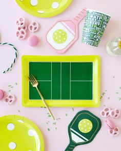 a table topped with plates and utensils on top of a pink surface covered in confetti