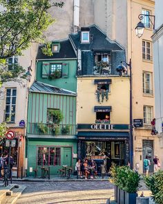 people are walking down the street in front of some buildings with windows and balconies