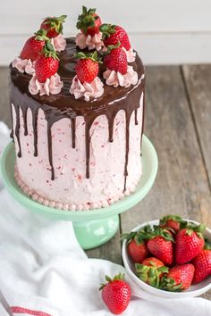 a cake with chocolate icing and strawberries next to it on a plate,