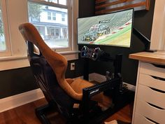 a gaming chair in front of a flat screen tv with racing cars on the screen