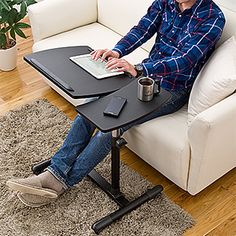 a man sitting at a table with a laptop on his lap and holding a coffee mug