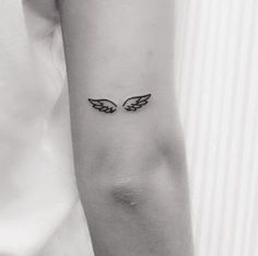 a woman's arm with an angel wing tattoo on the left side of her arm