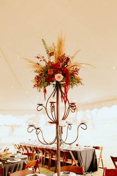 an elegant centerpiece is adorned with red flowers and greenery for a wedding reception