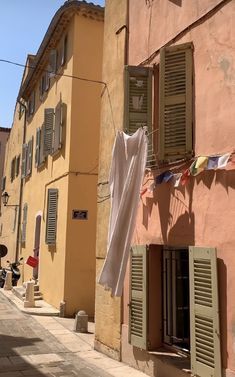 clothes hanging out to dry in front of an old building with shutters and windows