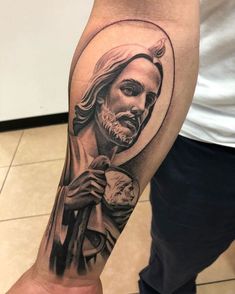 a man with a tattoo on his arm holding a clock and wearing a jesus head