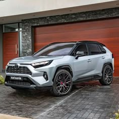 the new toyota rav is parked in front of a garage with two red doors