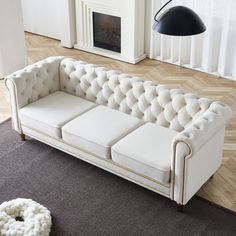 a white couch sitting on top of a hard wood floor next to a fire place