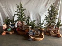 three small wooden boats with christmas trees in them on a wood table next to a white backdrop