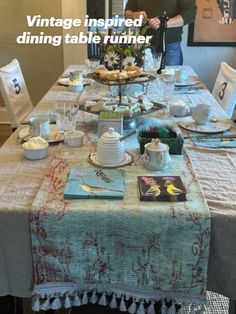 the table is set with tea cups, plates and other things on it for people to eat