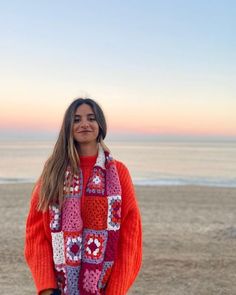 a woman is standing on the beach with her hand in her pocket