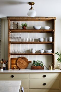 a wooden shelf filled with lots of dishes and glasses on top of a kitchen counter