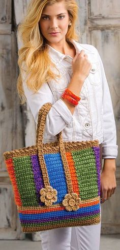 a woman holding a multicolored crocheted bag