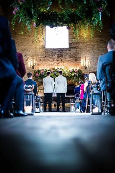 two men in suits standing at the end of a wedding ceremony with candles lit behind them