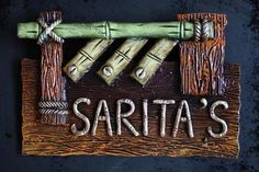 a wooden sign that says sarita's with bamboo poles and ropes on it