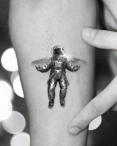 a person with a small tattoo on their leg that is shaped like an astronaut's body