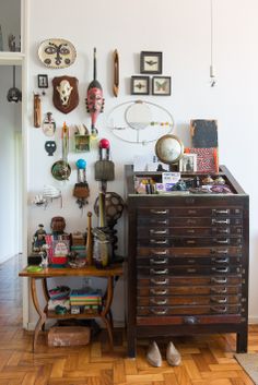 there are many clocks on the wall above this old dresser and other things in the room