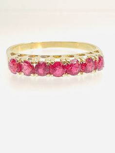 a yellow gold ring with pink stones on the inside and outside, sitting on a white surface