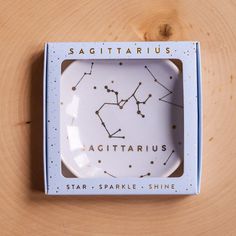 a zodiac sign plate in a box on a wooden surface with the words sagittarius above it