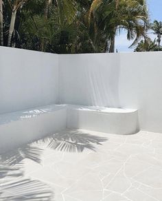 an outdoor area with white walls and palm trees