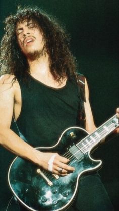 a man with long hair playing an electric guitar