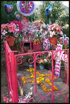 there is a pink gate with flowers on it and balloons in the air behind it