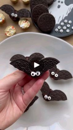 someone is holding up an oreo cookie shaped like a bat with googly eyes