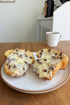 two chocolate chip muffins on a plate with one cut in half to show the inside