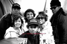 a group of young people standing next to each other in front of a wall with posters on it