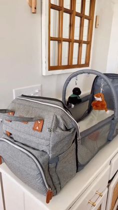 a grey duffle bag sitting on top of a white dresser next to a mirror