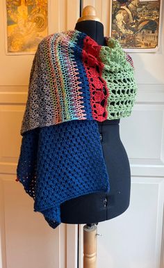 a crocheted shawl is displayed on a mannequin