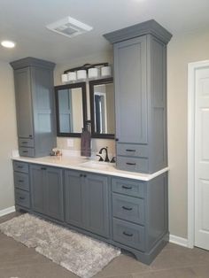 a large bathroom with gray cabinets and white counter tops, along with a rug on the floor