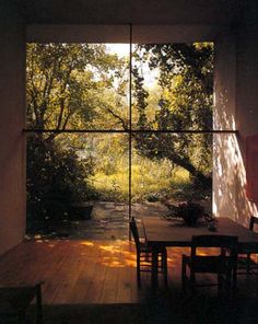 a table and chairs are in front of a large window with the sun shining through it