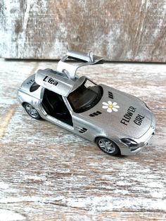 a silver toy car sitting on top of a wooden table