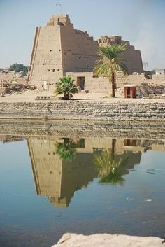 an ancient building is reflected in the water