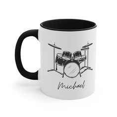 a black and white coffee mug with a drum set on it's side that says michael