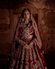 a woman in a red and gold bridal gown standing with her hands on her hips