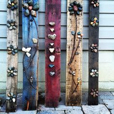 four wooden planks with hearts and flowers painted on them, sitting in front of a house