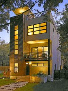 a modern house with stairs leading up to the second floor and two story windows at night