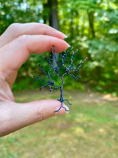 a hand holding a tiny blue tree branch