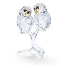 two crystal owls sitting on top of a tree