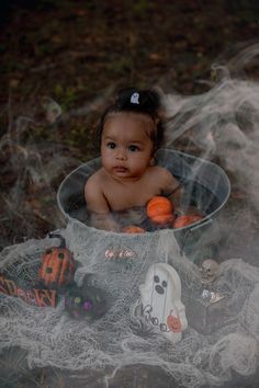 a baby sitting in a bucket with halloween decorations