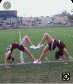 two cheerleaders doing handstand on the sidelines