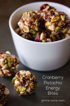 cranberry pistachio energy bites in a white bowl next to some nuts