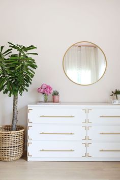 a white dresser sitting next to a potted plant