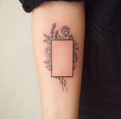 a woman's arm with a tattoo on it that has flowers and a rectangle in the middle