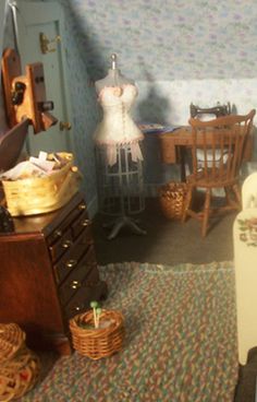 a dollhouse bedroom with clothes and furniture in it's display case, next to a bed