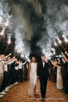 a newly married couple walking down the aisle with their guests holding sparklers in front of them